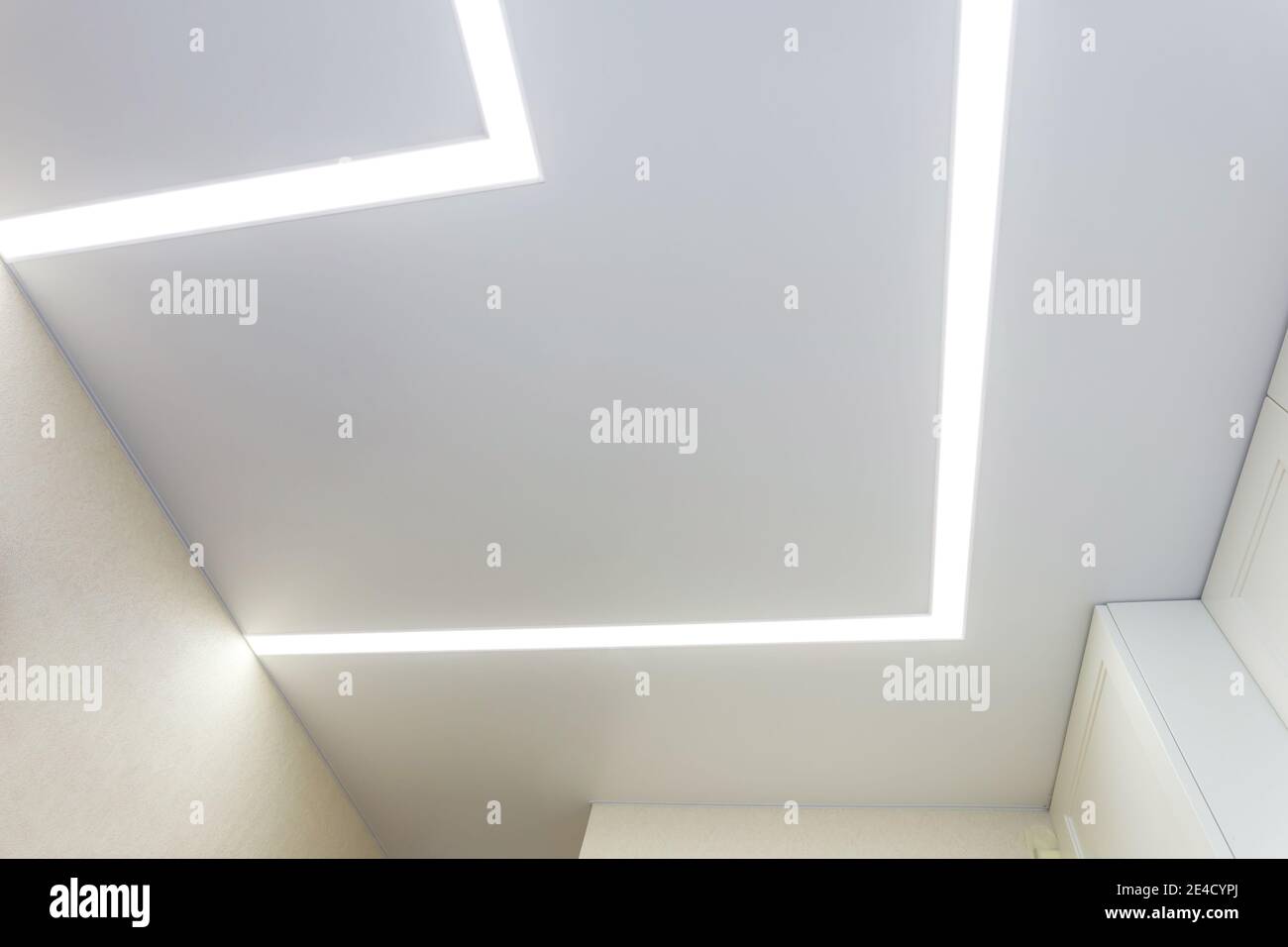 Abgehängte Decke mit Halogenstrahlern und Trockenmauerkonstruktion im leeren Raum in Wohnung oder Haus. Stretchdecke weiß und komplex. Stockfoto