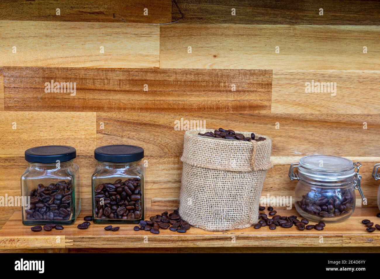 Transparente Gläser mit Kaffeebohnen auf dem Tisch. Nahaufnahme von verschiedenen Kaffeesorten in Behältern in Reihe. Café-Konzept Stockfoto