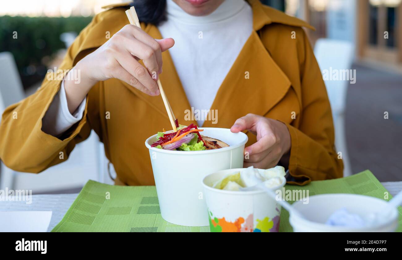 Frau mit Nudeln Mahlzeit mit Essstäbchen im Restaurant aus Der Papierkarton wird ganz in der Nähe angezeigt Stockfoto