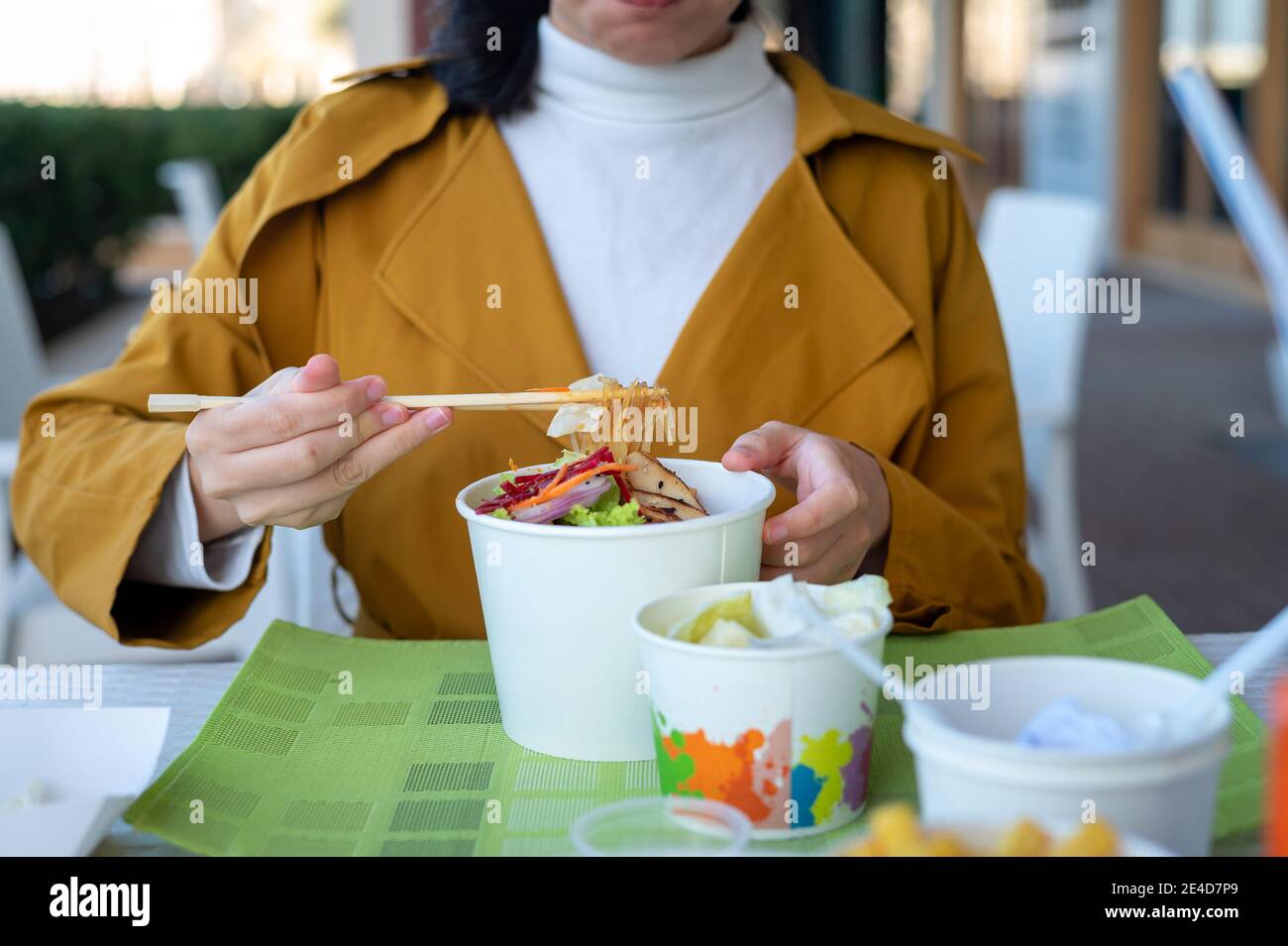 Frau mit Nudeln Mahlzeit mit Essstäbchen im Restaurant aus Der Papierkarton wird ganz in der Nähe angezeigt Stockfoto