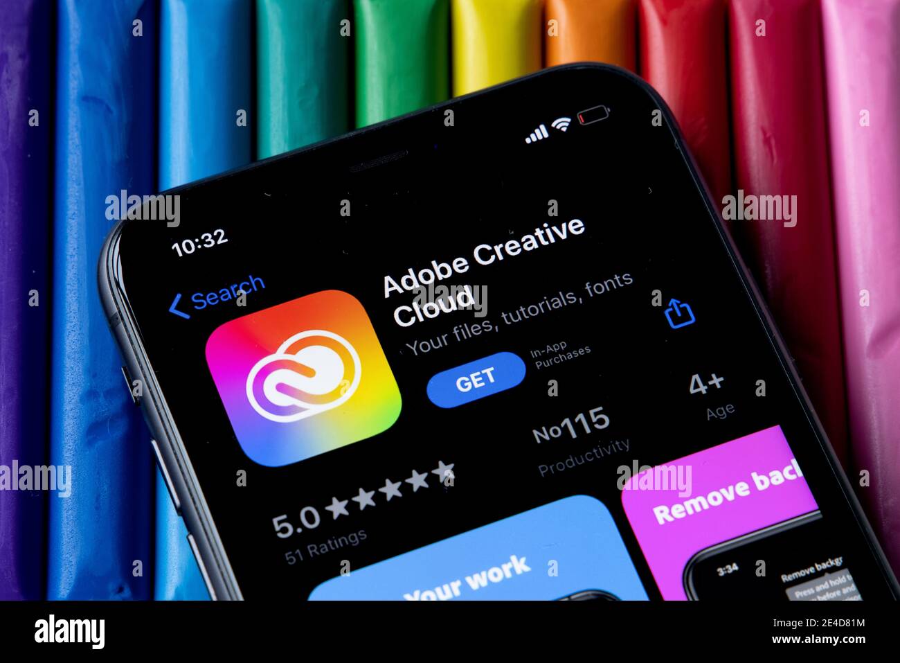 Mobile Adobe Creative Cloud-App im AppStore mit einem bunten Hintergrund aus Plastilin. Installation der Creative Cloud auf dem iPhone. Stockfoto