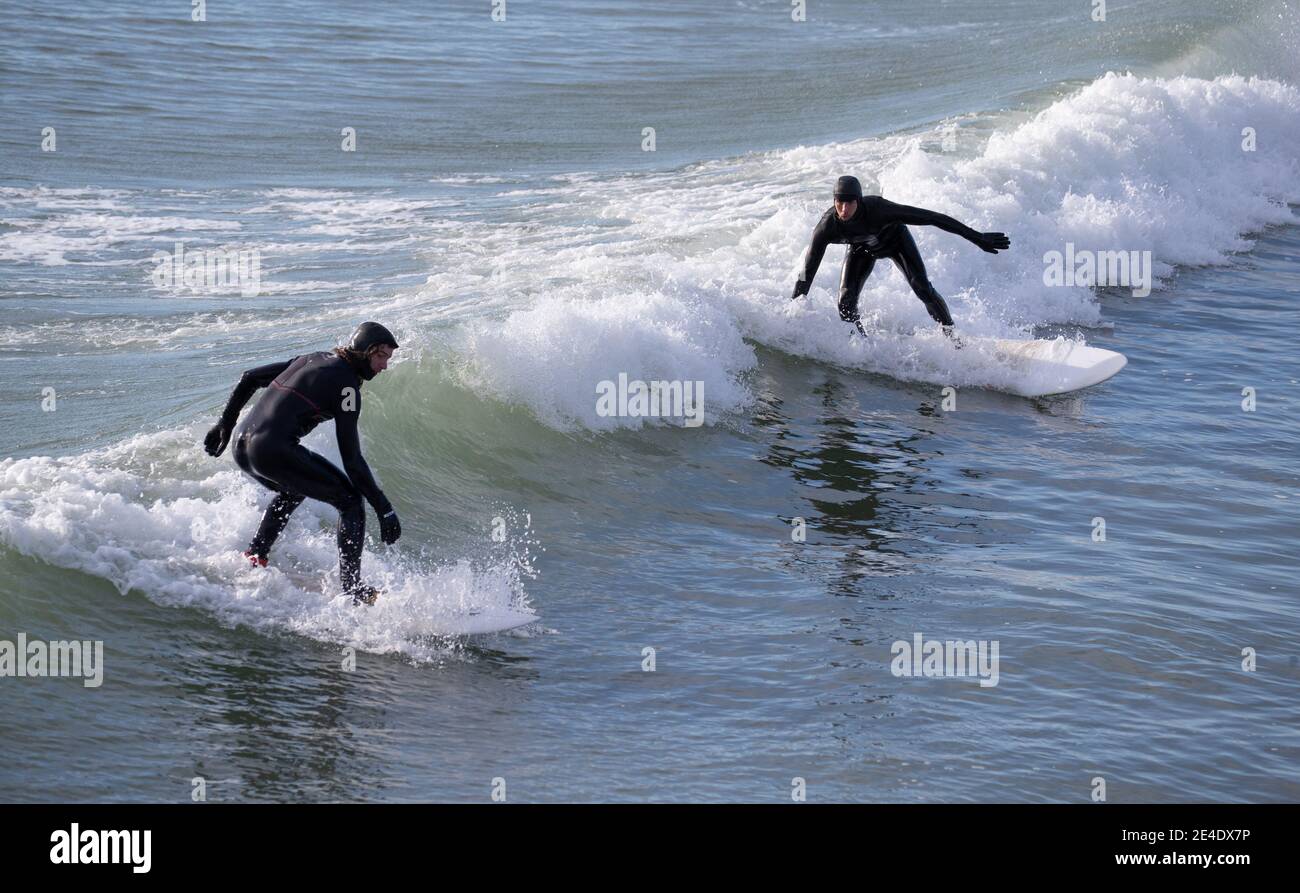 Surfer reiten eine Welle im Meer vor dem Bournemouth Beach in Dorset, während Englands dritter nationaler Lockdown, um die Ausbreitung des Coronavirus einzudämmen. Bilddatum: Samstag, 23. Januar 2021. Stockfoto