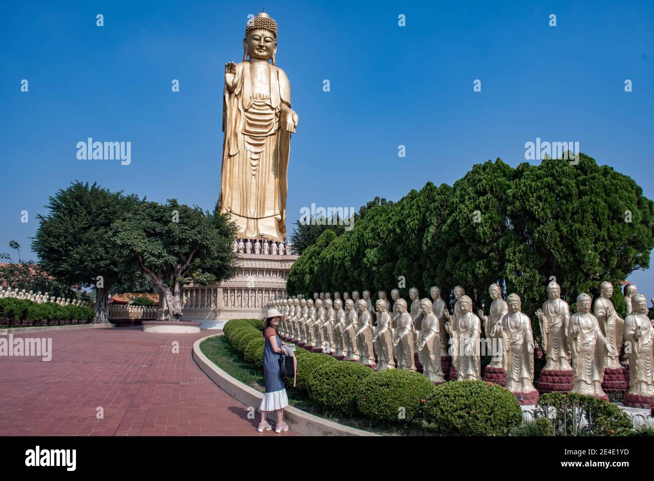 Gebet und Blick auf die goldene Buddha-Statue und die riesige große Buddha-Statue im Hintergrund im Kloster Fo Guang Shan in Kaohsiung Taiwan Stockfoto