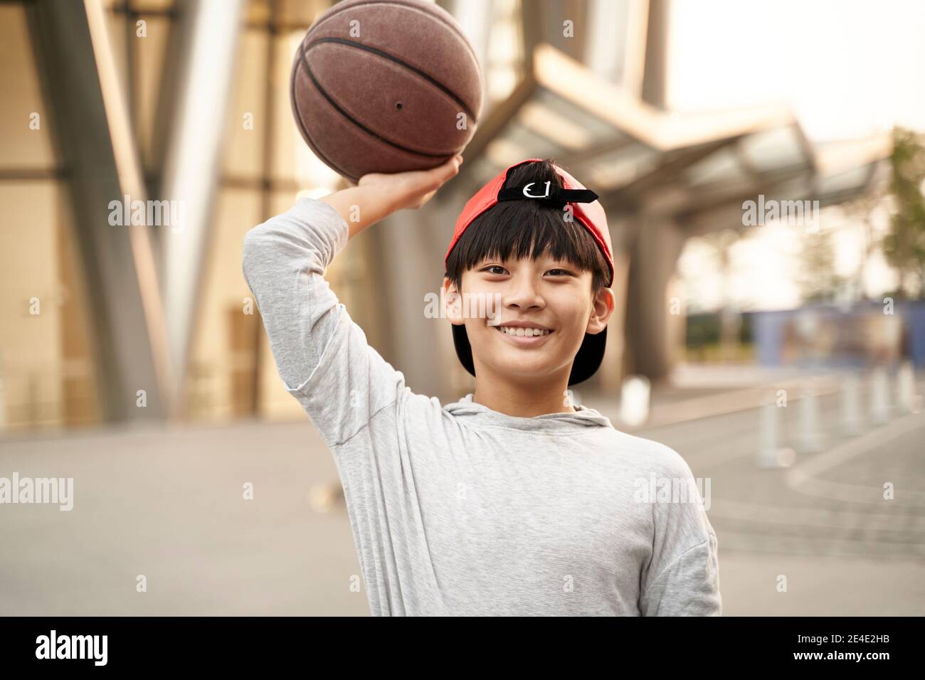 Outdoor-Porträt eines glücklichen fünfzehnjährigen asiatischen Teenager-Basketballspieler Stockfoto
