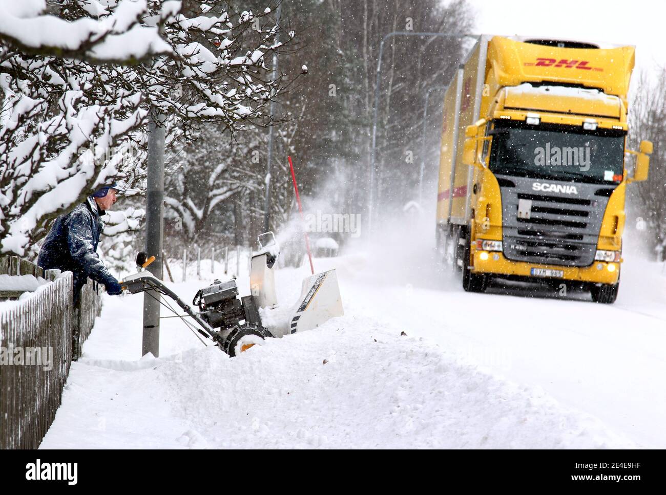 VADSTENA, SCHWEDEN - 6. DEZEMBER 2012: Jemand, der mit seiner Schneefräse Schnee entfernt. Ein LKW, der auf einer Winterstraße vorbeifährt. Foto Jeppe Gustafsson Stockfoto