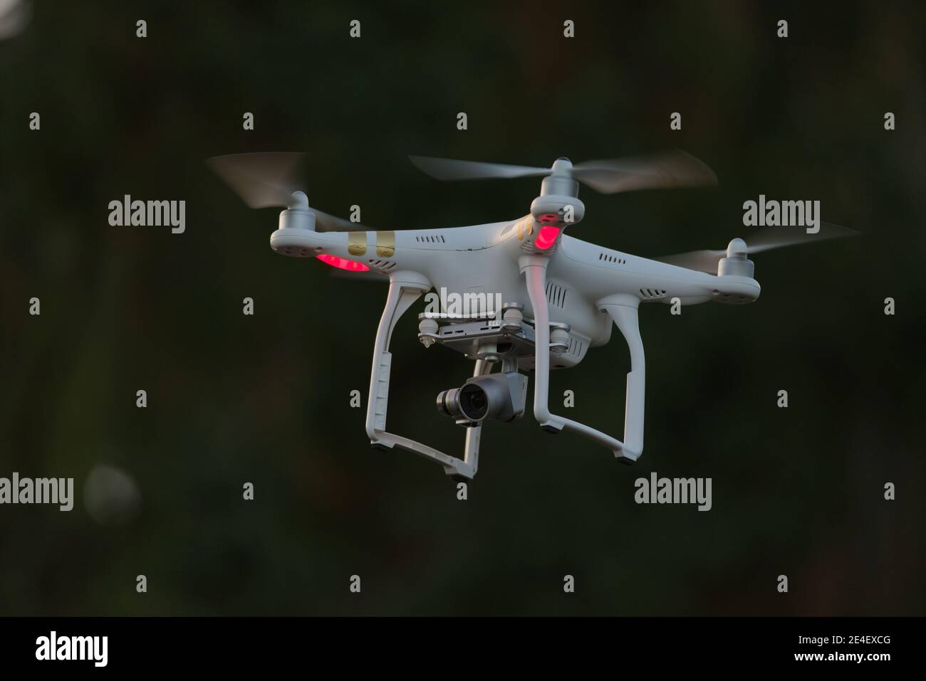 20 - isolierte Quadcopter-Kamera Drohne mit Digitalkamera. Schlichter dunkler Hintergrund mit selektivem Fokus, der die helle weiße Drohne als Motiv hinterlässt. Stockfoto