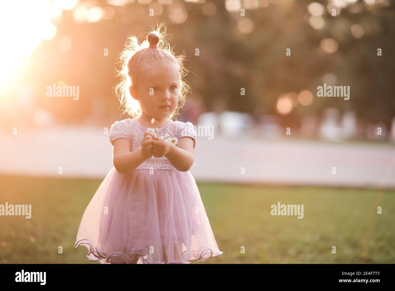 Nettes Baby Mädchen 2-3 Jahre alt trägt Prinzessin Kleid hält Blume über  Stadt Hintergrund in sonnigen Tag. Kindheit Stockfotografie - Alamy