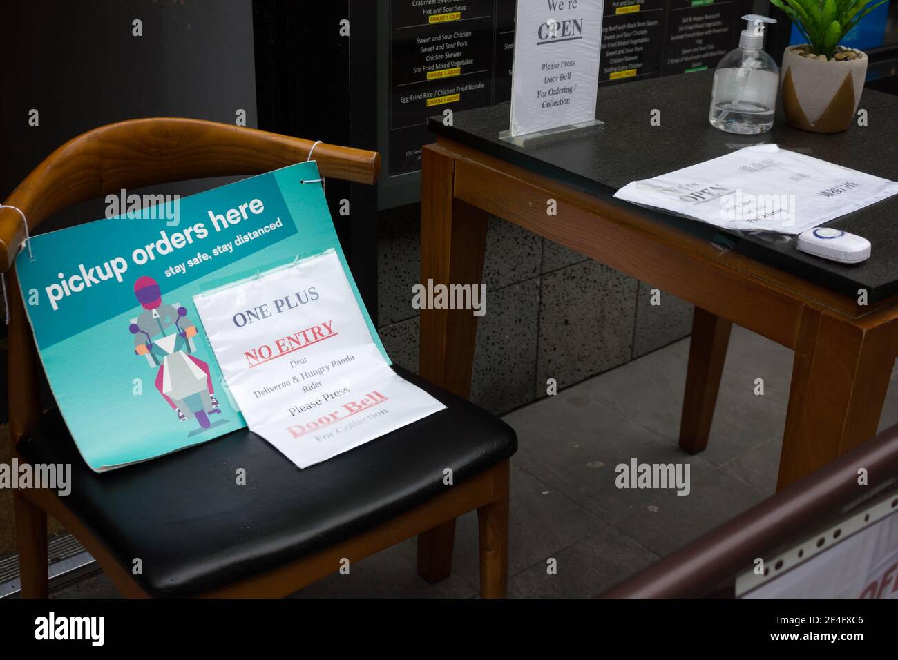 Restaurant eine Abholung Aufträge hier Zeichen auf Stuhl und Türklingel auf dem Tisch für Mitnahme Kunden oder Lieferer, London China Stadt West End Stockfoto