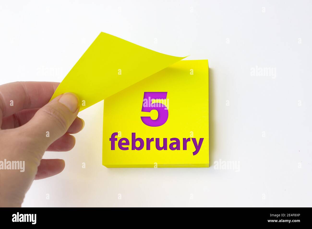 Februar. Tag 5 des Monats, Kalenderdatum. Die Hand reißt das gelbe Blatt des Kalenders ab. Winter Monat, Tag des Jahres Konzept Stockfoto