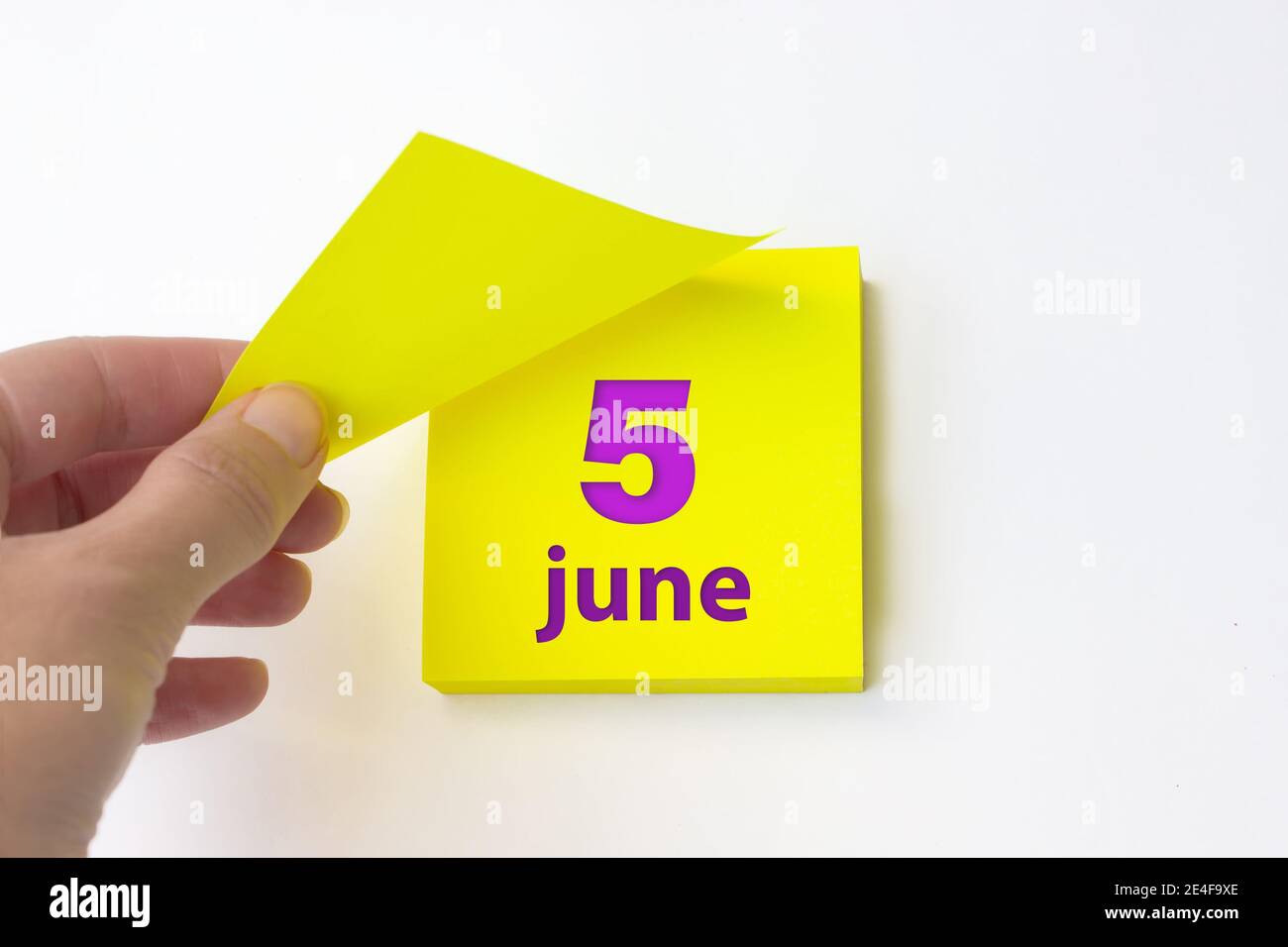 Juni. Tag 5 des Monats, Kalenderdatum. Die Hand reißt das gelbe Blatt des Kalenders ab. Sommer Monat, Tag des Jahres Konzept Stockfoto