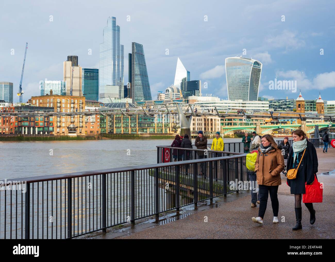 London-Leute, die an einem Wintertag in London, Großbritannien, am South Bank River Path oder Southbank entlang der Themse mit Blick über die City of London spazieren Stockfoto