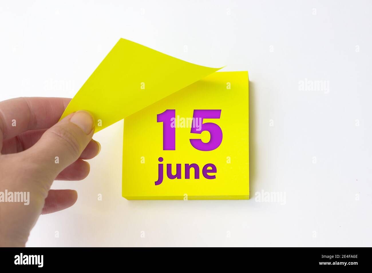 Juni. Tag 15 des Monats, Kalenderdatum. Die Hand reißt das gelbe Blatt des Kalenders ab. Sommer Monat, Tag des Jahres Konzept Stockfoto