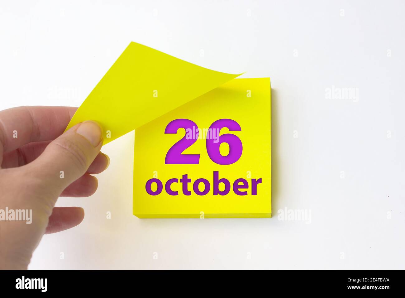 Oktober. Tag 26 des Monats, Kalenderdatum. Die Hand reißt das gelbe Blatt des Kalenders ab. Herbst Monat, Tag des Jahres Konzept Stockfoto