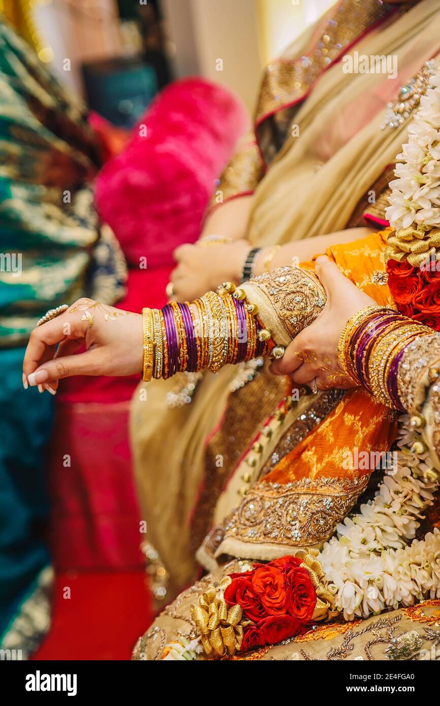 Nahaufnahme indischen pakistanischen Braut Hände mit goldenen Henna in Gelbes Kleid tragen viele Schmuck Armbänder während mehndi Hochzeitsfeier Stockfoto
