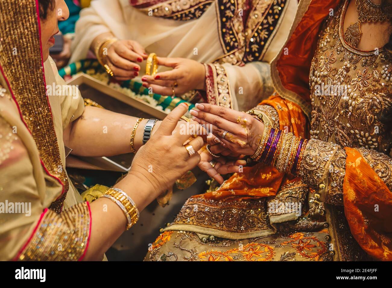 Schwiegermutter Hilfe für indische pakistanische Braut zu tragen goldene Schmuck Armbänder und Ringe während Henna mehndi sangeet Damen Partynacht Stockfoto