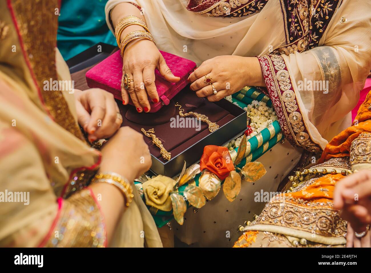 Ältere Frauen öffnen Samtboxen mit goldenen Schmuckohrringen Für indische Braut während der Hochzeit Henna mehndi sangeet Party-Nacht Stockfoto