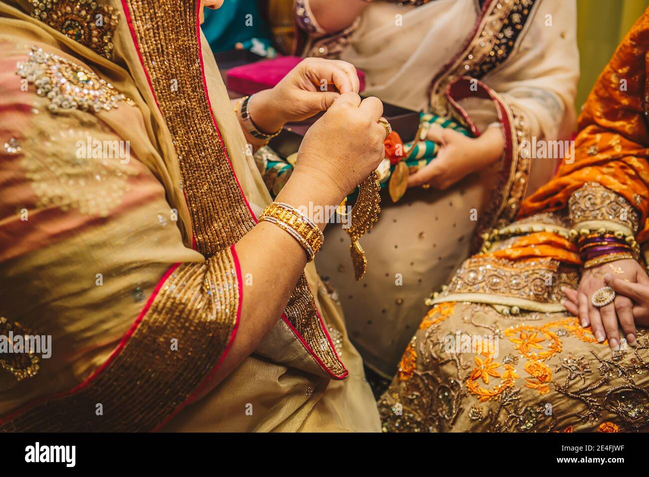 Schwiegermutter Hände gehen zu goldenen Schmuck Halskette tragen Auf Braut während Henna mehndi sangeet indisch pakistanischen weiblichen Partei Nacht Stockfoto