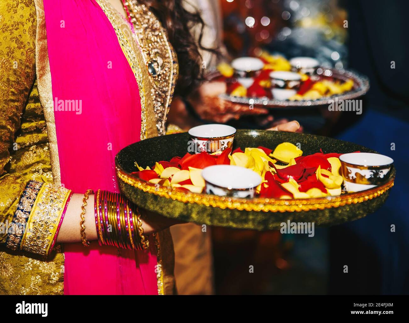 Indische Mädchen halten runde Teller mit Blütenblättern und Tassen Eine Hochzeit Henna mehndi sangeet Party Stockfoto