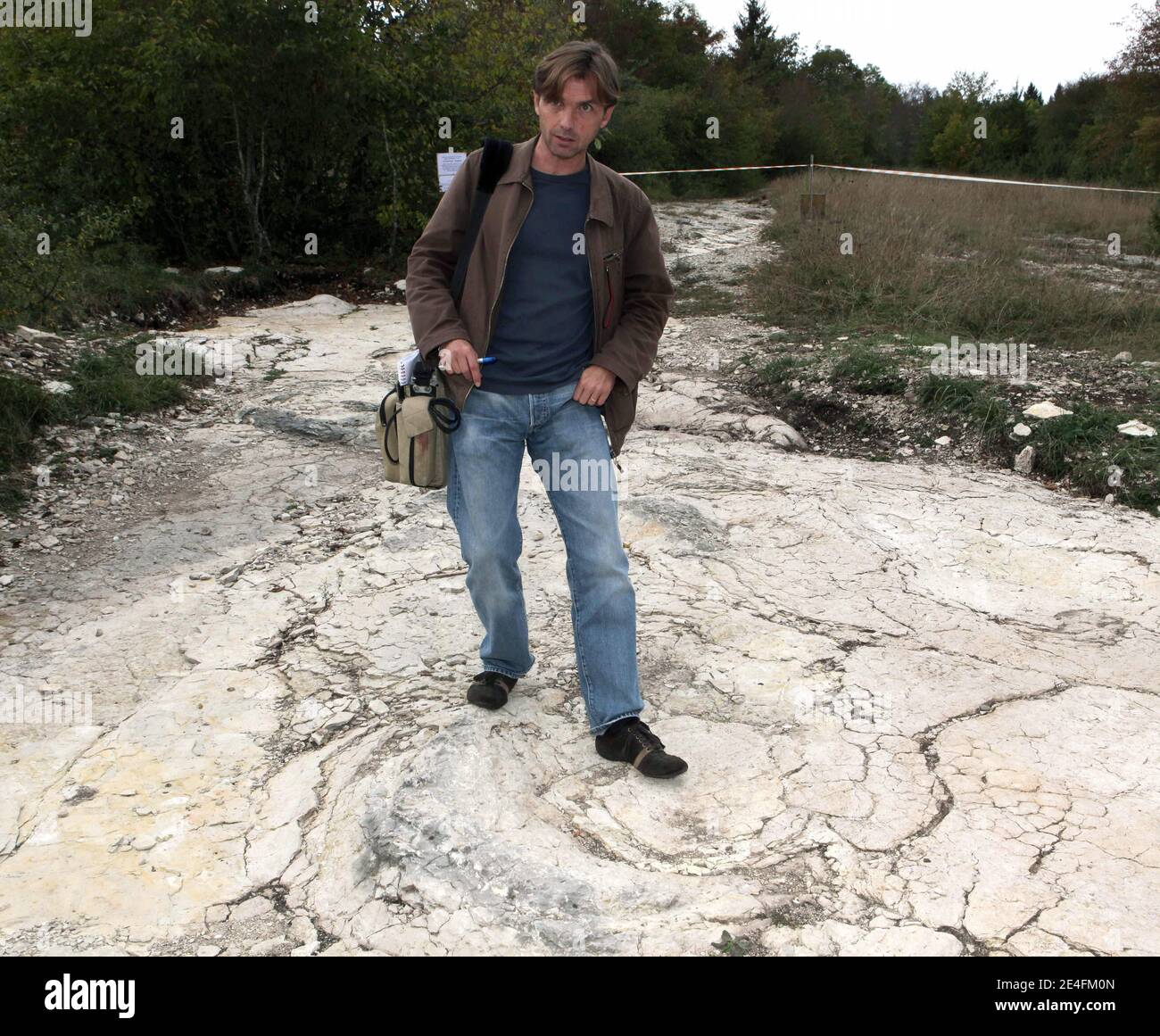 Ein Journalist, der vor der jüngsten Entdeckung eines gut erhaltenen Sauropoden-Dinosaurier-Fußabdrucks zwischen 1.5 und zwei Metern Durchmesser am 6. Oktober 2009 in der Nähe von Plagne, Jura, Ostfrankreich, steht. Die Entdeckung, die im April gemacht wurde und vor 150 Millionen Jahren stammt, wurde von Wissenschaftlern als einzigartige Entdeckung bestätigt. Dies könnten die größten Sauropoden Dinosaurier Spuren jemals in der Welt entdeckt, nach dem National Research French council (CNRS).Foto von Vincent Dargent/ABACAPRESS.COM Stockfoto