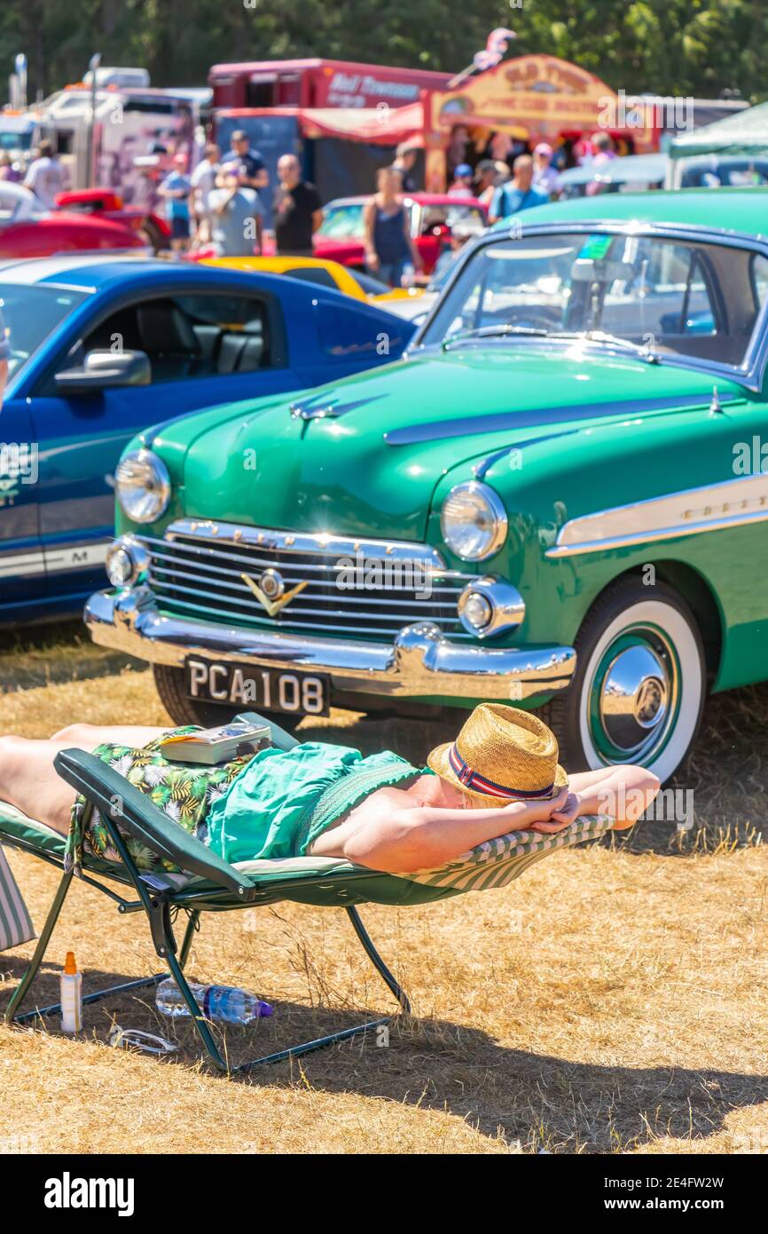 Mann, der sich länger in der Sonne entspannt, neben dem klassischen Amerikaner der 1940er Jahre Auto bei Stars & Stripes klassische amerikanische Auto-Show Tatton Parken Stockfoto