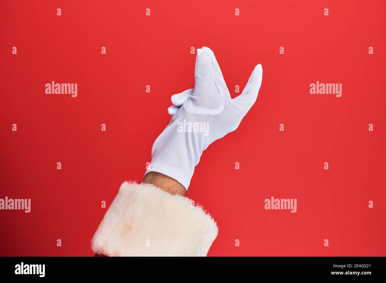 Hand eines Mannes trägt weihnachtsmann Kostüm und Handschuhe über rotem Hintergrund Schnappfinger für den Erfolg, einfach und klicken Symbol Geste mit der Hand Stockfoto