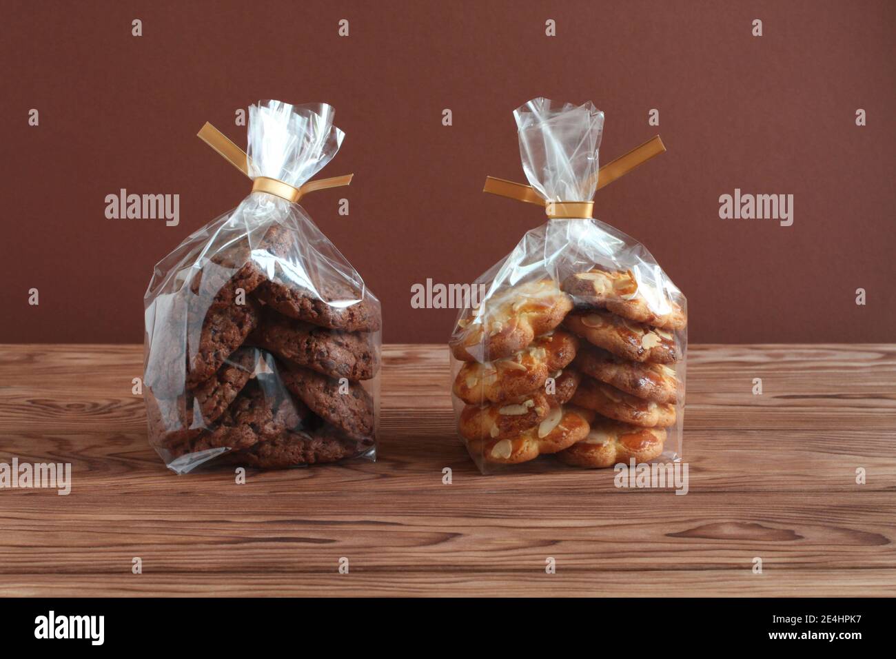 Schokoladen-Haferflocken-Kekse und Shortbread-Kekse mit Mandelflocken in transparenten Tüten auf einem Holztisch. Nahaufnahme Stockfoto