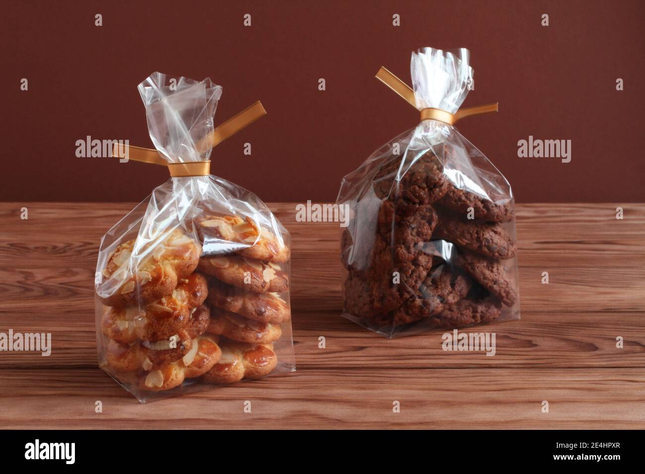 Schokoladen-Haferflocken-Kekse und Shortbread-Kekse mit Mandelflocken in transparenten Tüten auf einem Holztisch. Nahaufnahme Stockfoto