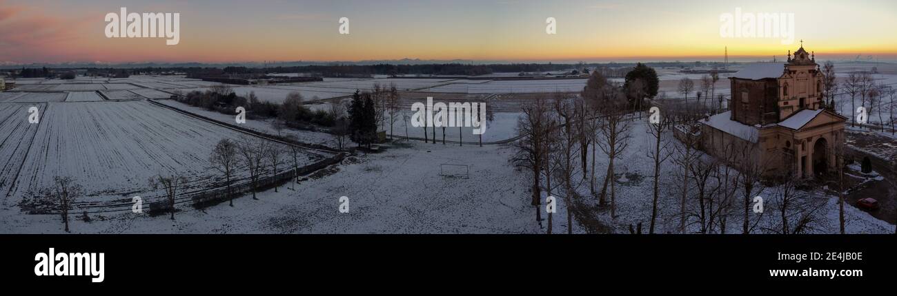 Die Sonne geht über der schneebedeckten Ebene und dem Heiligtum von Varallino di Galliate, Novara, Piemont, Italien Stockfoto
