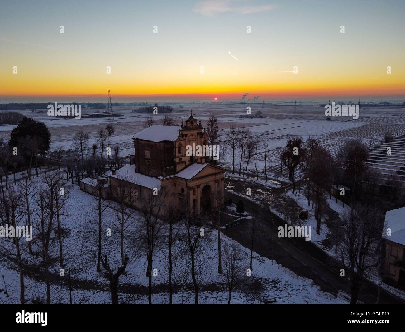 Die Sonne geht über der schneebedeckten Ebene und dem Heiligtum von Varallino di Galliate, Novara, Piemont, Italien Stockfoto