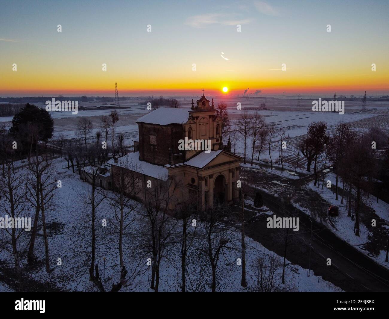 Die Sonne geht über der schneebedeckten Ebene und dem Heiligtum von Varallino di Galliate, Novara, Piemont, Italien Stockfoto