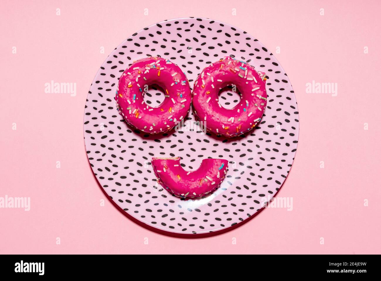 Anthropomorphe Gesicht aus Teller und rosa Zucker bestreut Donuts Stockfoto