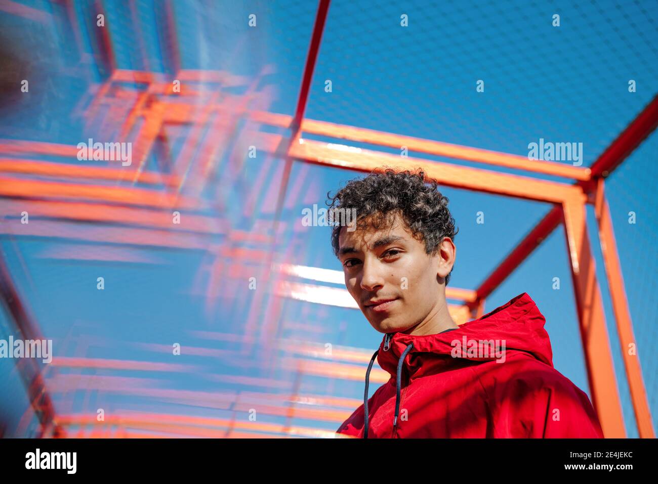 Junger Mann mit roter Kapuze gegen klaren blauen Himmel Stockfoto