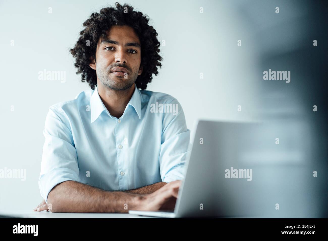 Selbstbewusster junger männlicher Unternehmer, der mit einem Laptop am Schreibtisch sitzt Büro Stockfoto