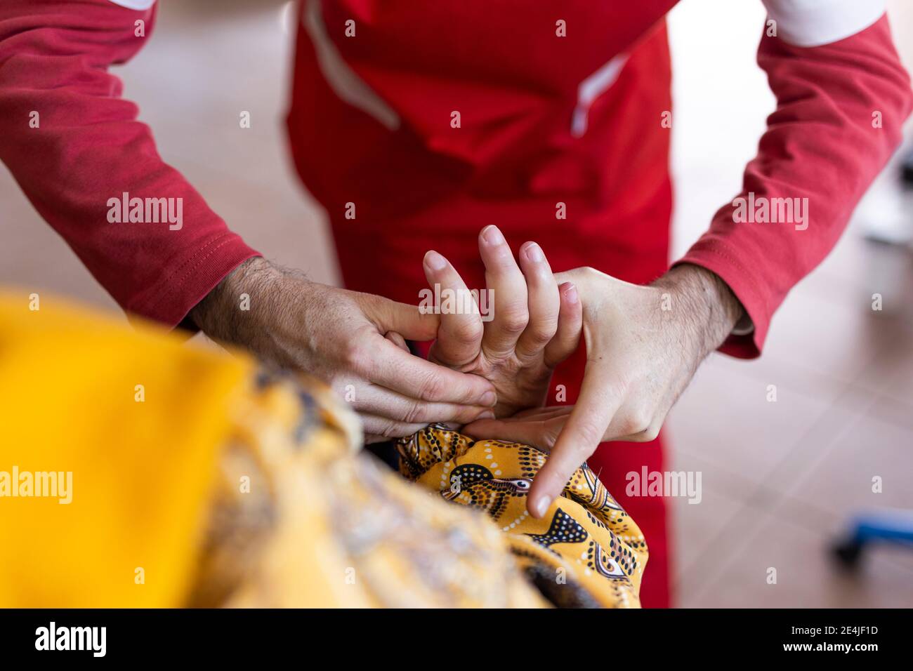 Männliche Krankenschwester, die die Finger einer behinderten Frau bei der Rehabilitation massiert Zentrieren Stockfoto