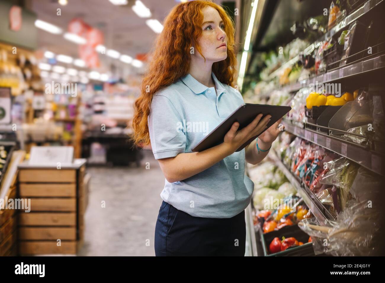 Frau mit einem digitalen Tablet während der Inventarkontrolle in einem Lebensmittelgeschäft. Auszubildende Mitarbeiterin im Supermarkt. Stockfoto