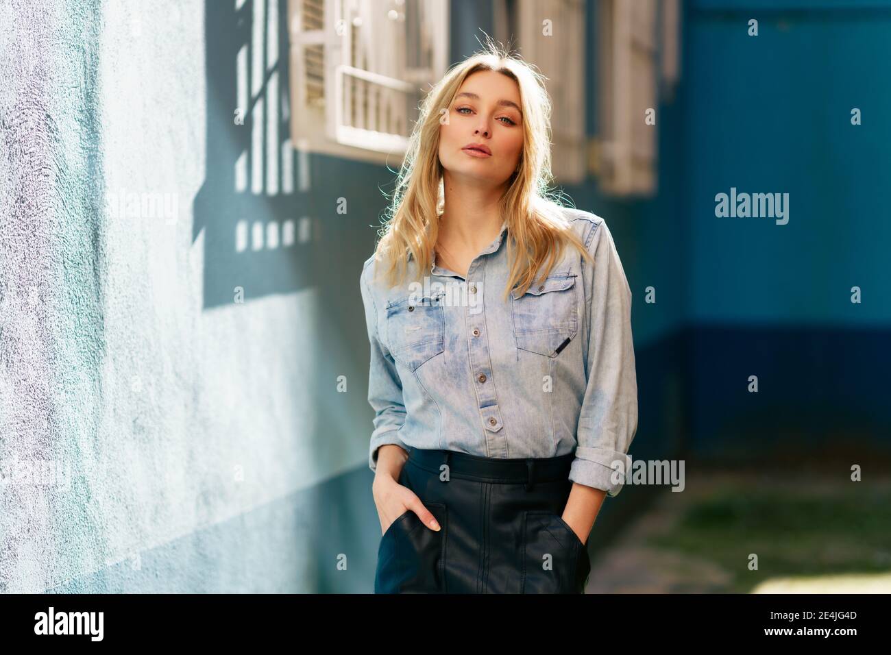 Blonde Frau trägt Jeanshemd und schwarzen Lederrock in der Straße stehen  Stockfotografie - Alamy