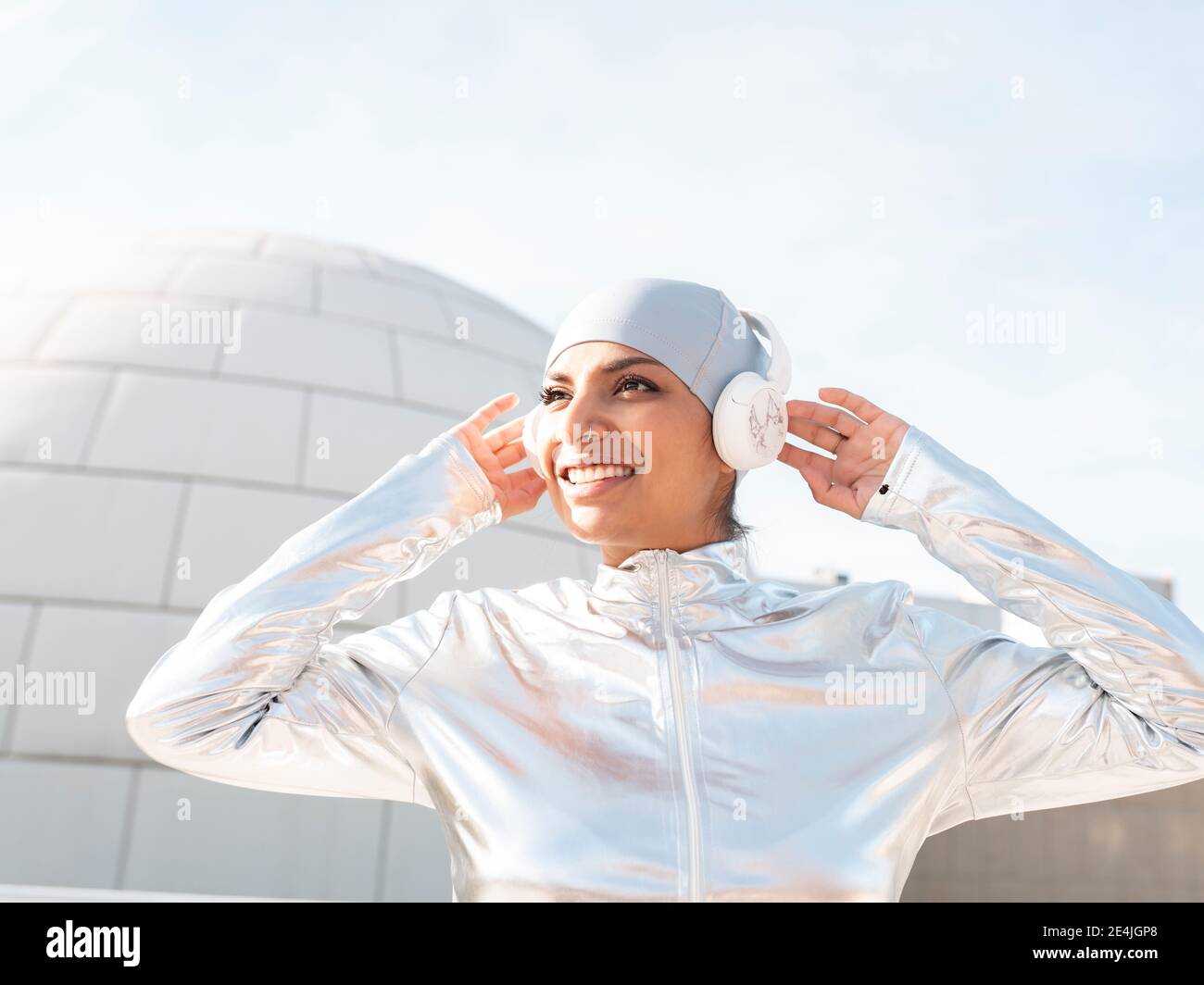 Junge Frau in glänzendem Schutzanzug mit OK-Schild, während sie gegen Iglu steht Stockfoto
