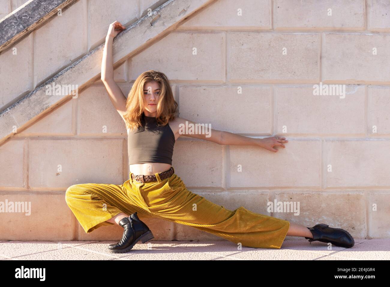 Junge Frau, die draußen an der Steinmauer tanzt Stockfoto