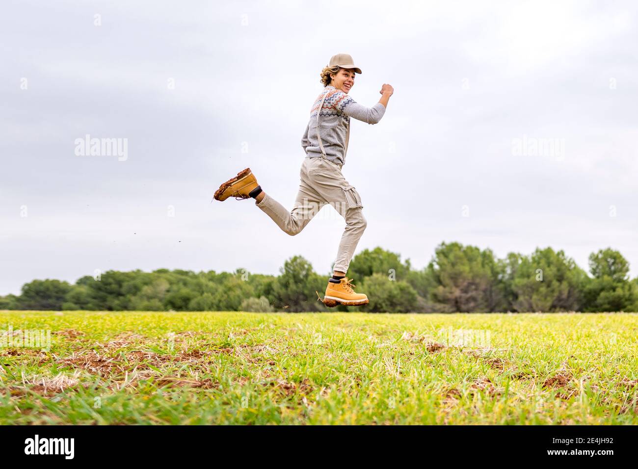 Junger Mann springt und posiert mitten in der Luft in grasbewachsenen Feld Stockfoto