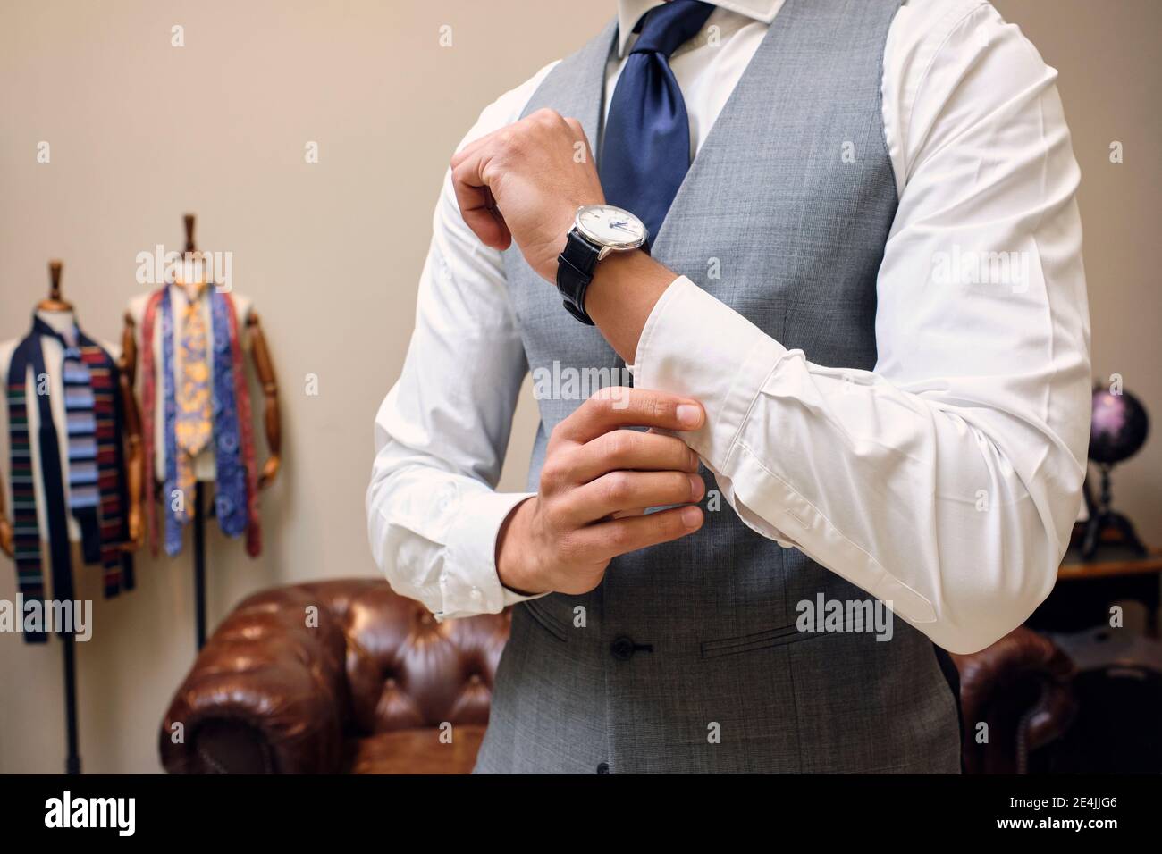 Mann in grau Weste Befestigung Hemdmanschette in Schneider Boutique Stockfoto