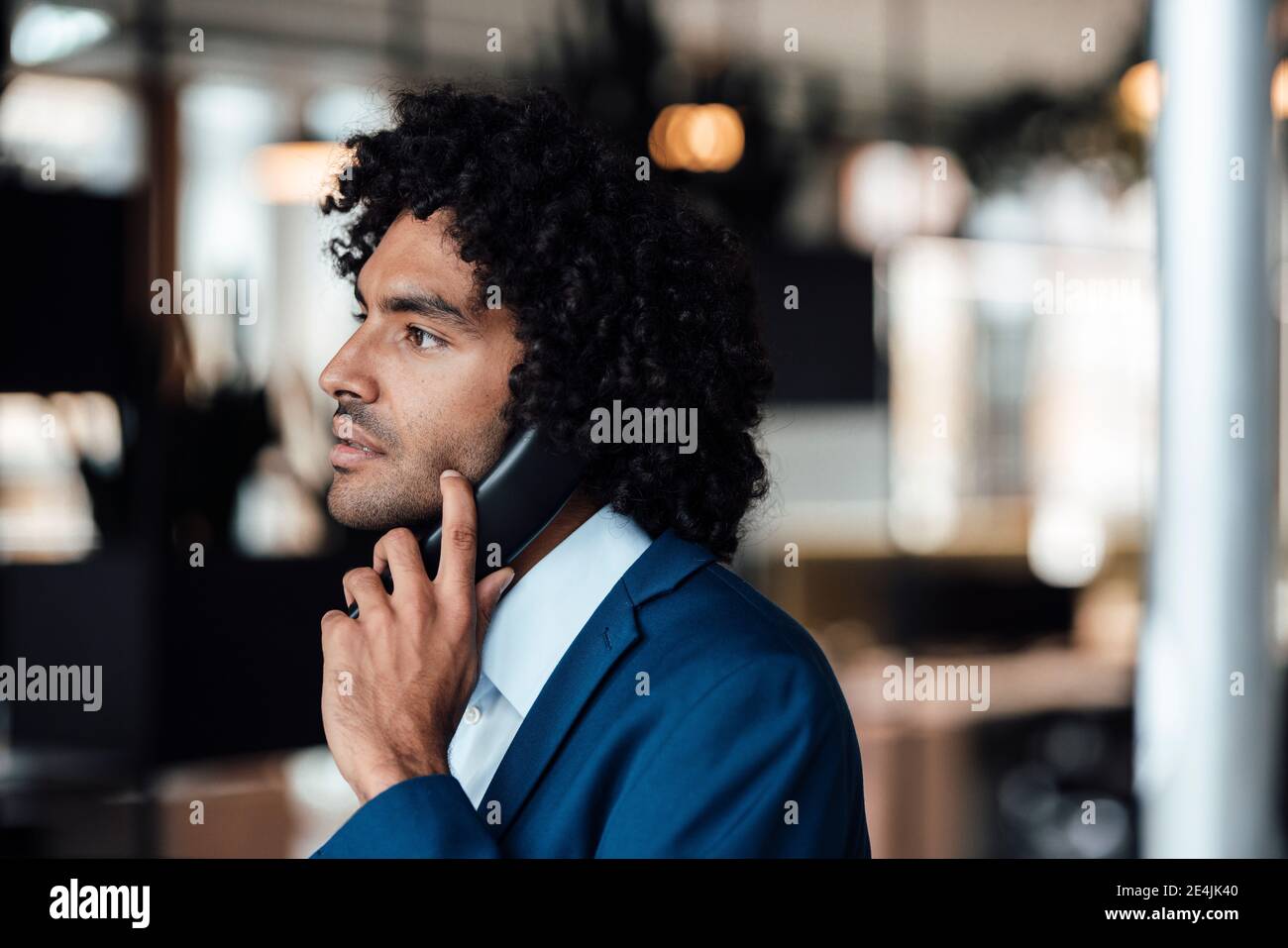 Junge männliche Unternehmer im Gespräch auf Festnetztelefon beim Blick weg Am Arbeitsplatz Stockfoto