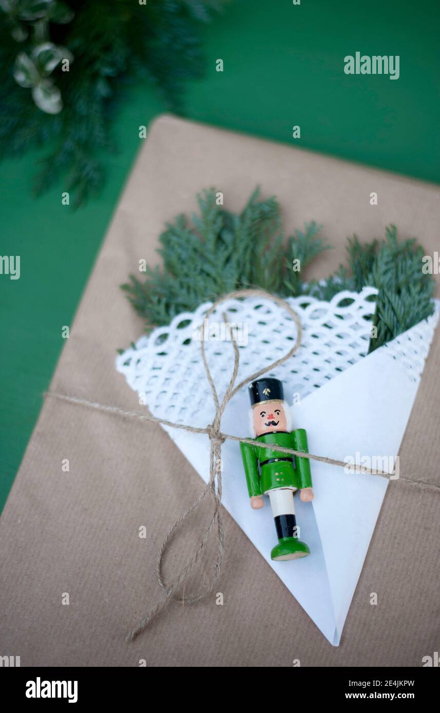 Geschenkpapier mit Tannenzweigen, Deckchen und kleiner Nussknacker-Figur  verziert Stockfotografie - Alamy