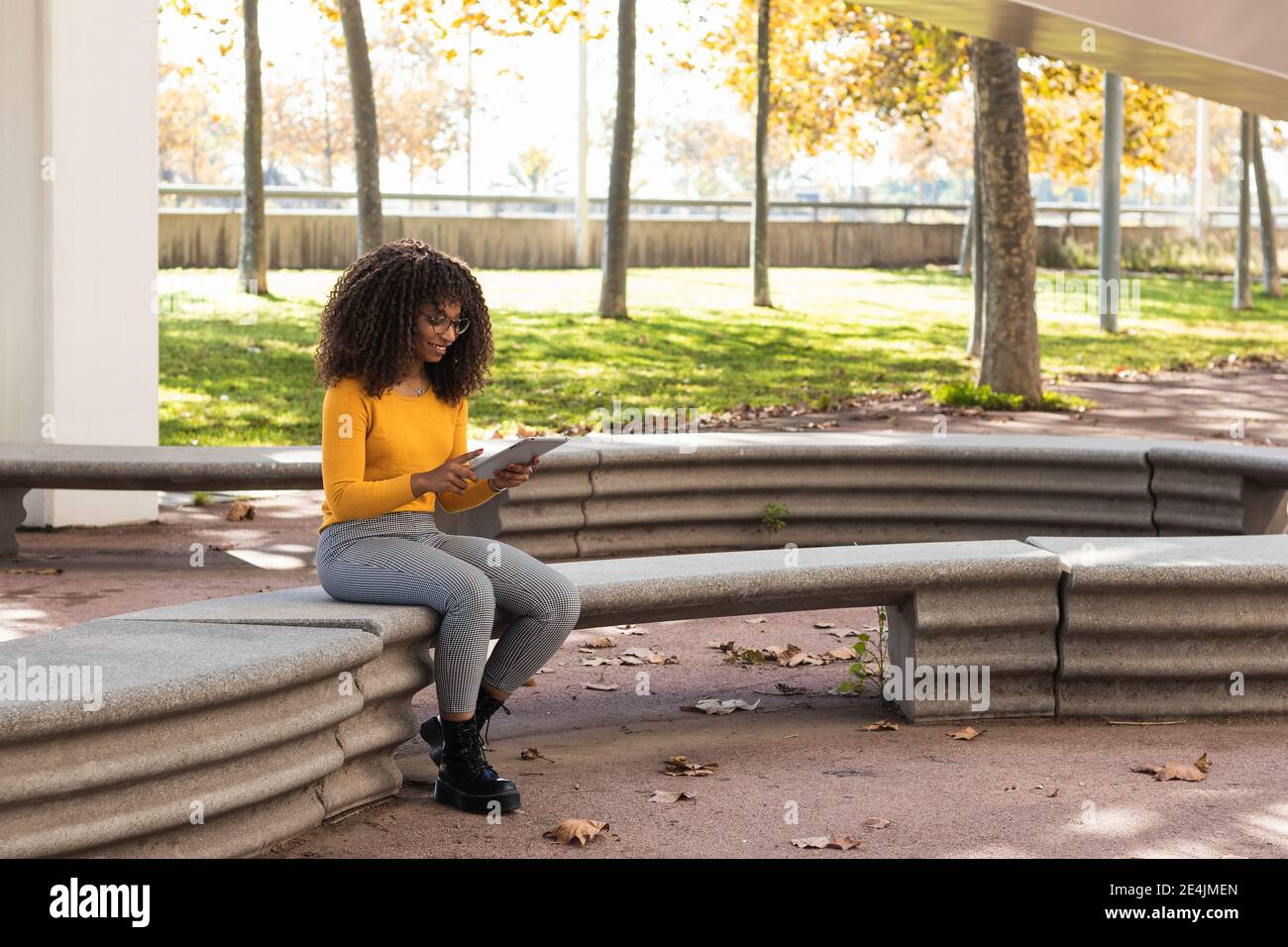 Afro Frau mit digitalen Tablet, während sie auf Stein Bank sitzen Im öffentlichen Park Stockfoto