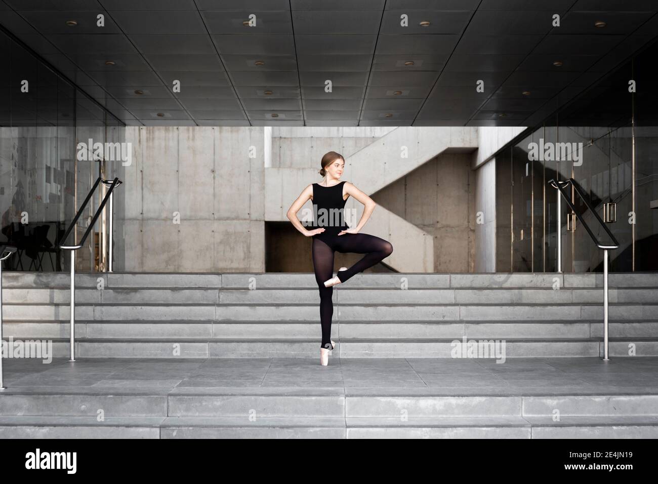 Ballerina in schwarzem Trikot in modernem Betongebäude Stockfoto