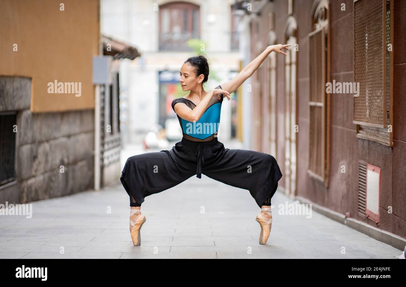 Tänzerin tanzt während sie Zehenspitzen auf dem Fußweg steht Stockfoto
