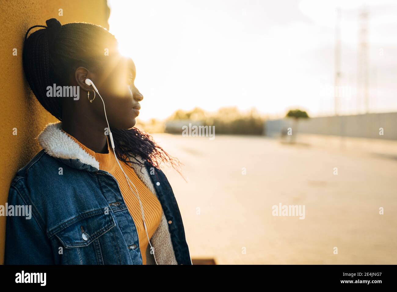 Teenager Mädchen Tag träumen, während Musik gegen Wand hören Straße Stockfoto