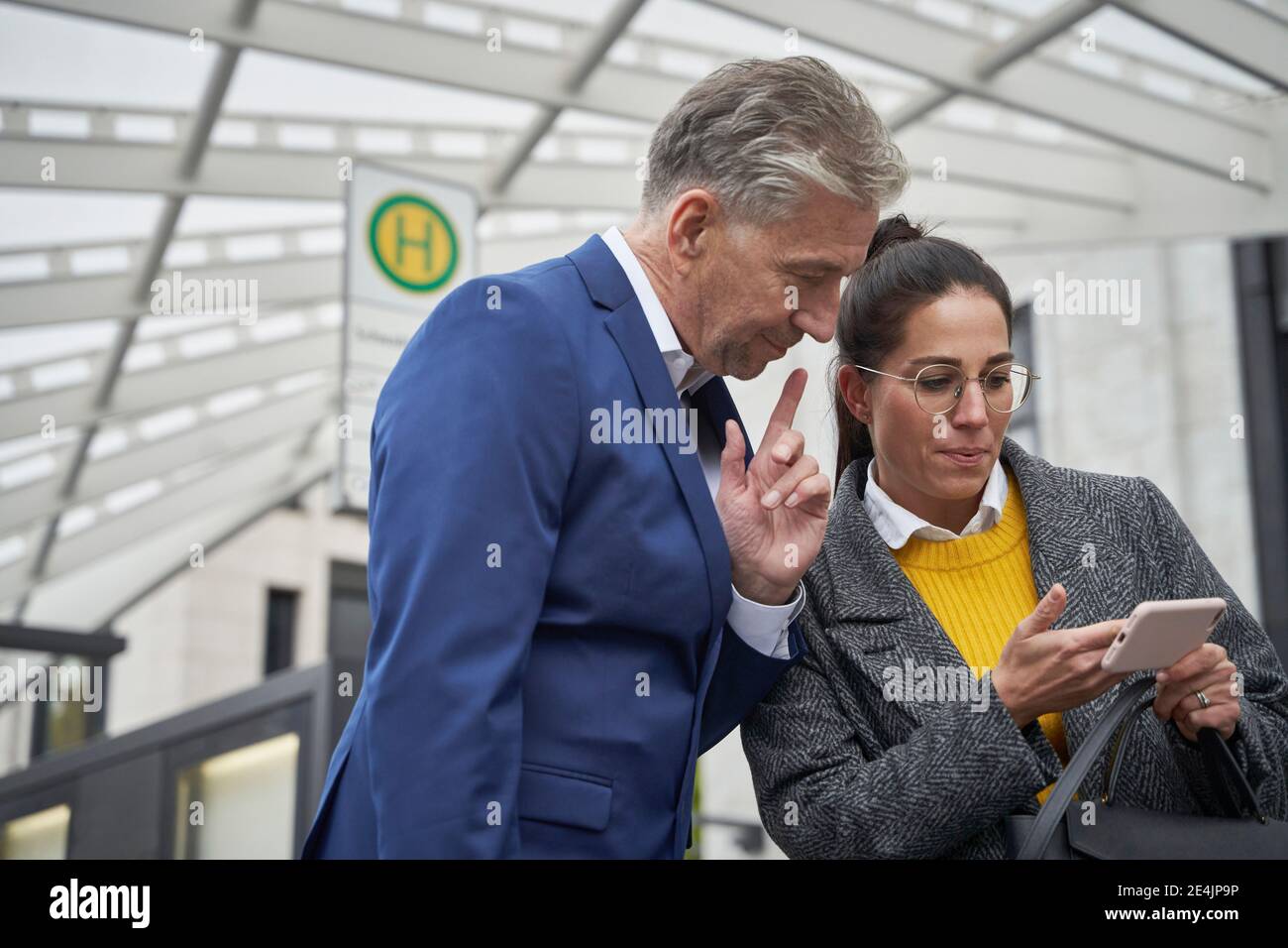 Geschäftsfrau, die ein Smartphone mit einem älteren männlichen Kollegen teilt Stockfoto