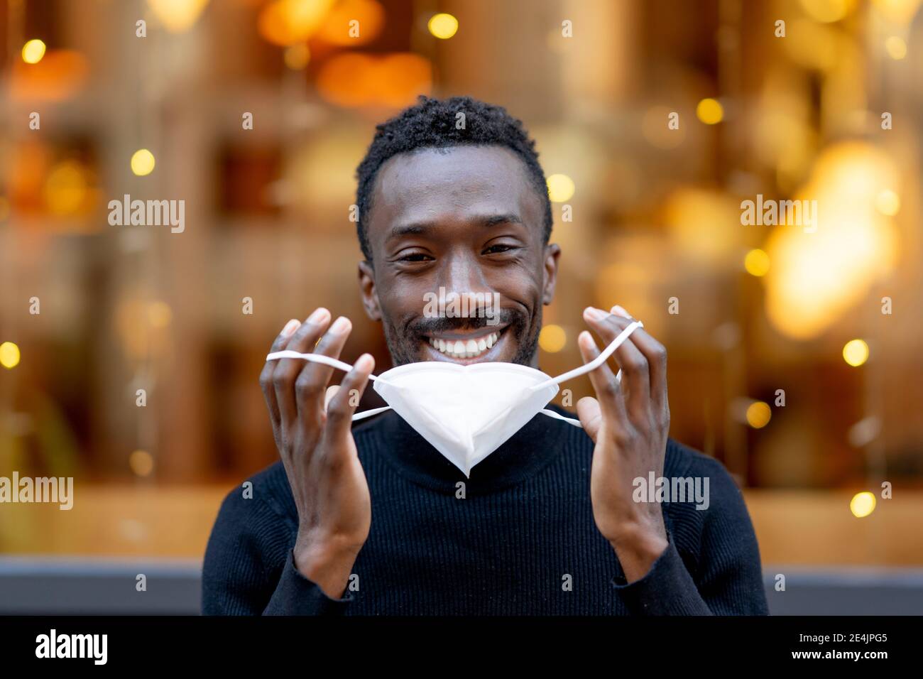 Lächelnder Mann, der im Freien steht und eine Gesichtsmaske trägt Stockfoto