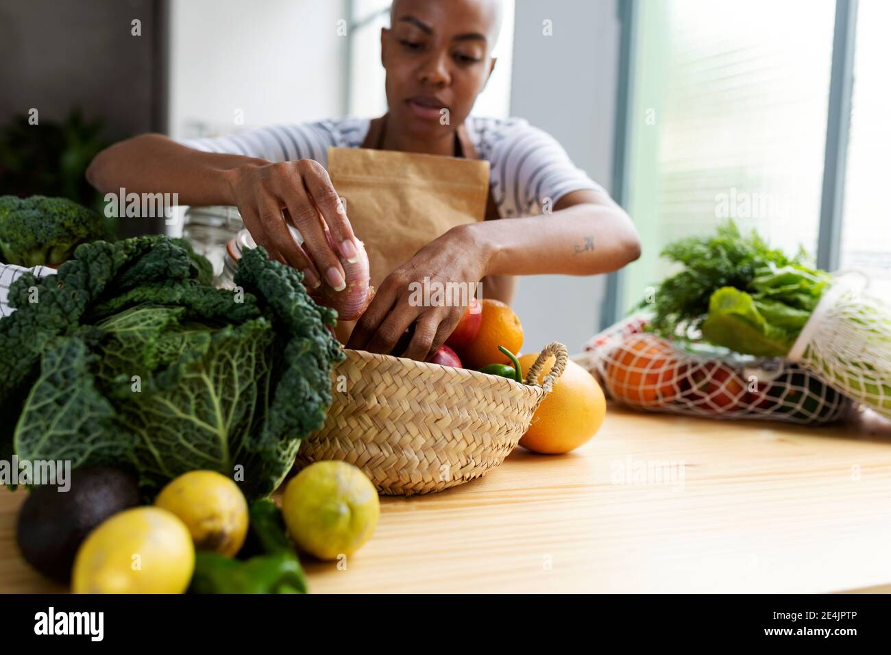 Frau mit Schürze in der Küche, Auspacken frisch gekauftes Bio-Obst und Gemüse Stockfoto