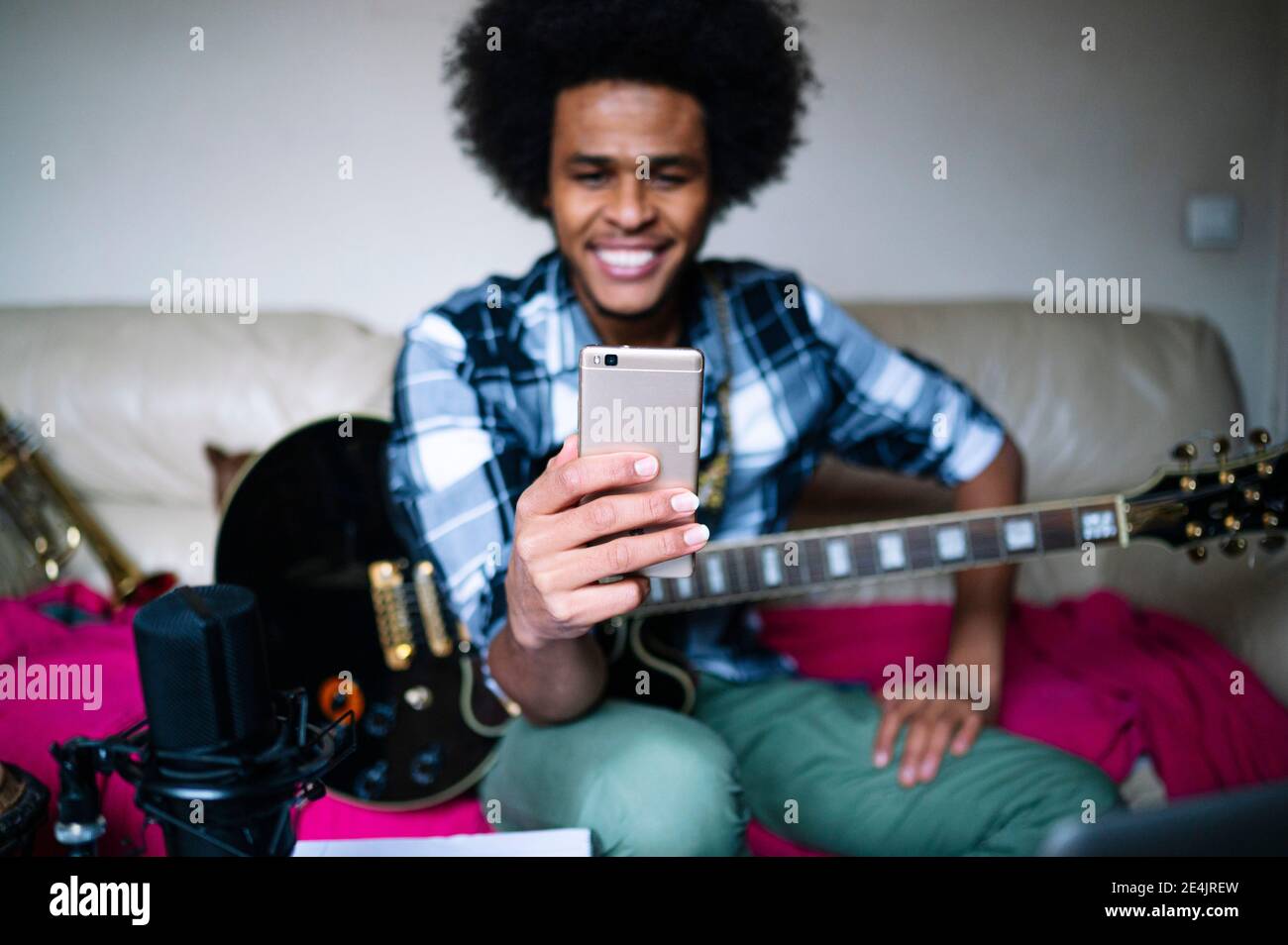 Fröhlicher afro junger Mann mit Trompete im blauen Raum Stockfoto